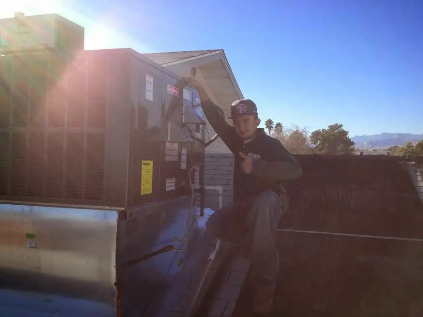 HVAC technician performing Air Duct Cleaning on a rooftop unit in Phelps